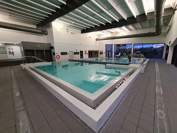 Piscinas de aprendizaje y spa, con escalerillas, barandillas de acceso y ventanales al fondo