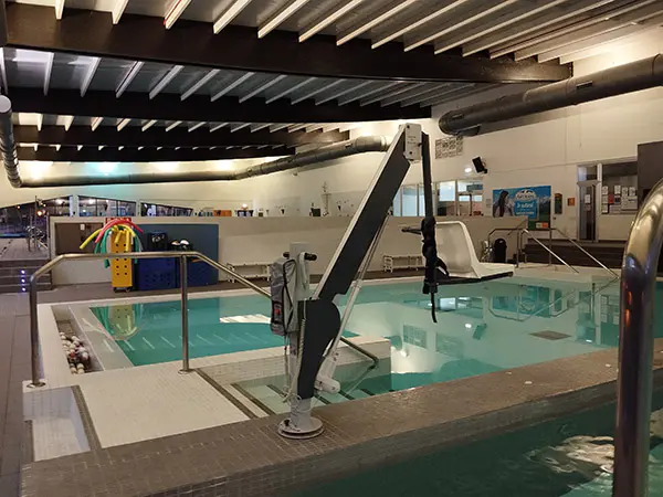 Piscina de spa, con escalerillas de acceso y grúa con asiento para baño de personas con movilidad reducida