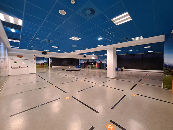 Panorámica general de una de las salas de actividades dirigidas, con vistas de las puertas de acceso y tarima del instructor