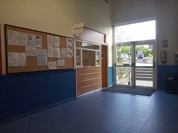 Puerta de acceso a las instalaciones y, junto a ella, una sala de información y un tablero de corcho con avisos
