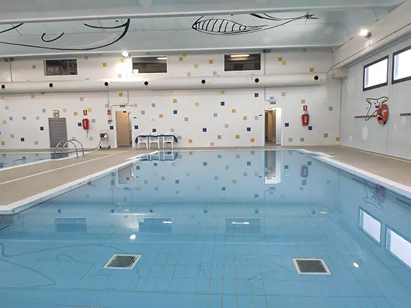 Panorámica de una de las dos piscinas de aprendizaje, con pinturas de animales en el techo y puertas de acceso al fondo
