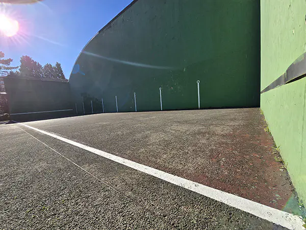 Vista a ras de suelo de la cancha de frontón, con la pared frontal al fondo